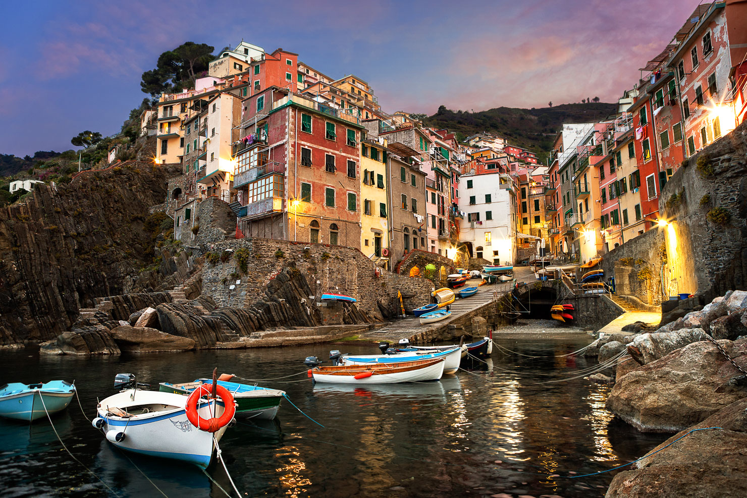 Cinque Terre harbor village at dusk with colorful buildings and boats