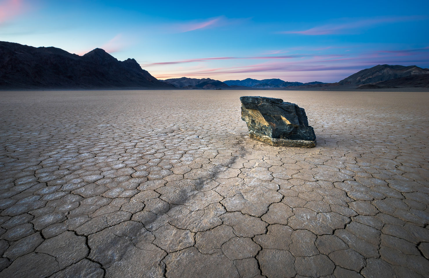 Sailing stone on cracked desert playa at sunset, Death Valley Racetrack